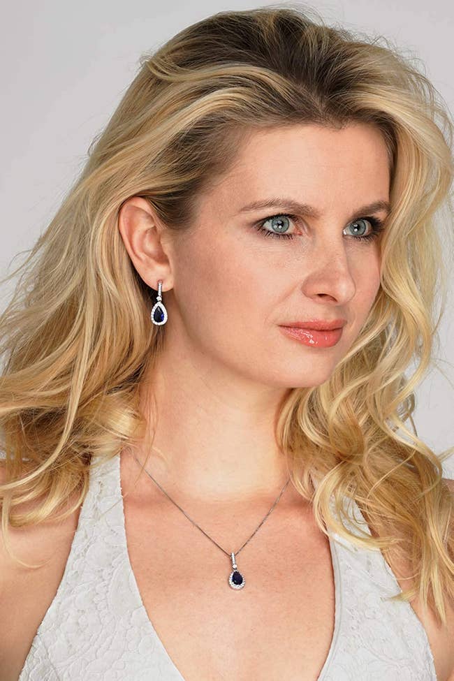 Model is wearing the pearl drop shaped earrings with deep blue sapphire gems on them and the necklace