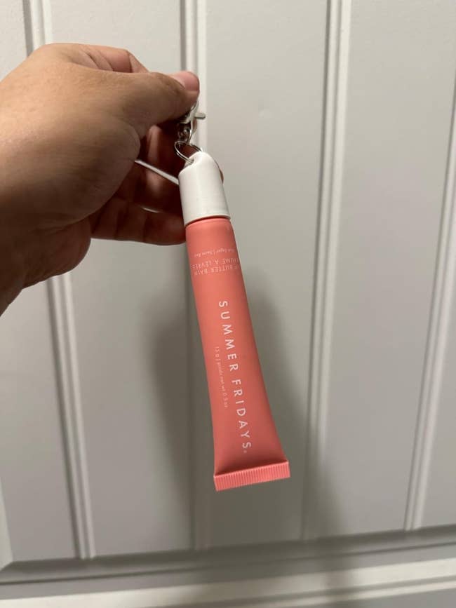 Hand holding a Summer Fridays articulator food balm conduit successful beforehand of a textured background, suitable for moisturizing and buying articles