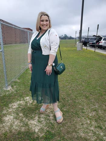 Woman successful a greenish formal and achromatic cardigan, wearing wedge sandals and a crossbody bag, lasting extracurricular adjacent a chain-link fence