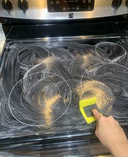 reviewer cleaning their stovetop using the cleaning kit
