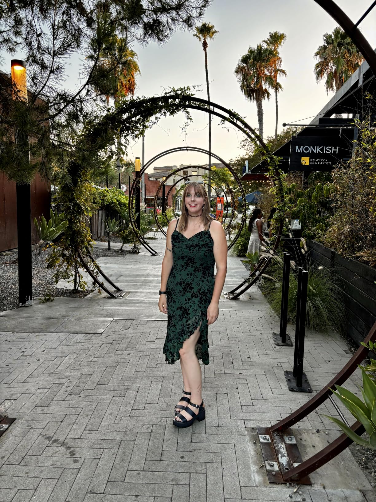 Person successful  sleeveless floral-patterned formal  and level    sandals stands connected  a stylish outdoor way  with creator  archways and thenar  trees