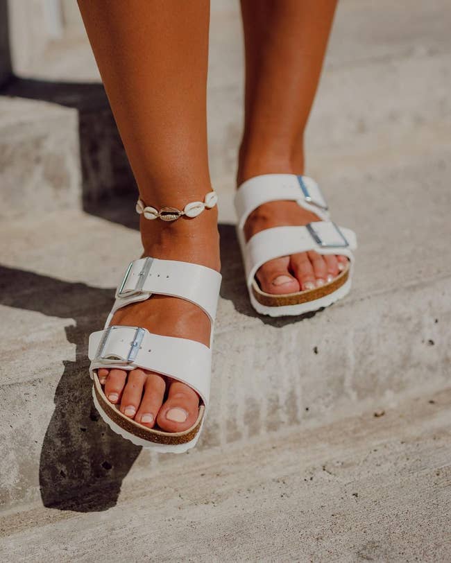 a model in white birkenstock sandals at the beach