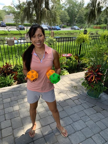 reviewer holds two orange dice and one green dice with different exercise movements on each