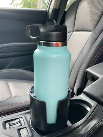 Reviewer's 32 oz water bottle in their cup holder adapter in their car