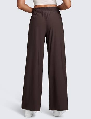 Person wearing wide-leg pants and achromatic  sneakers, viewed from the back