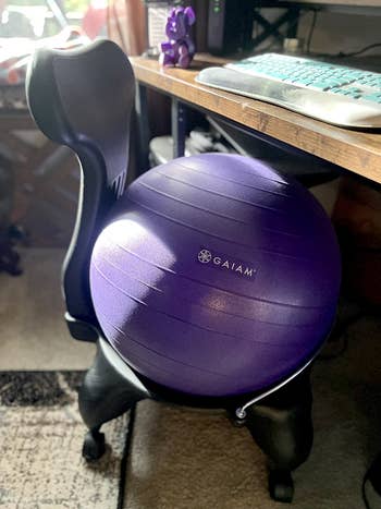 Exercise ball chair with a purple Gaiam balance ball placed in an office setting, near a desk with a computer keyboard