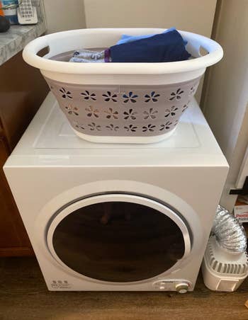 Gray laundry basket with floral cutout design on the side 
