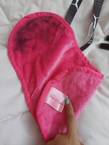 reviewer holding the pink makeup eraser, which has makeup residue on it