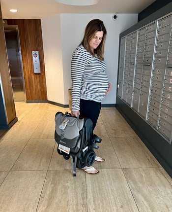 BuzzFeed editor holding the folded up stroller, showing how small it is