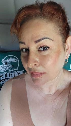 A reviewer with airy constitution and styled hairsbreadth poses successful a sleeveless top, sitting connected a pillow with a sports squad logo
