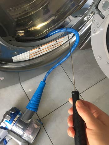 reviewer using the blue dryer vent cleaning attachment with their vacuum to clean their vent