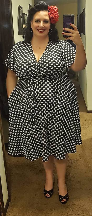 A reviewer wearing the dress in black with white polka dots