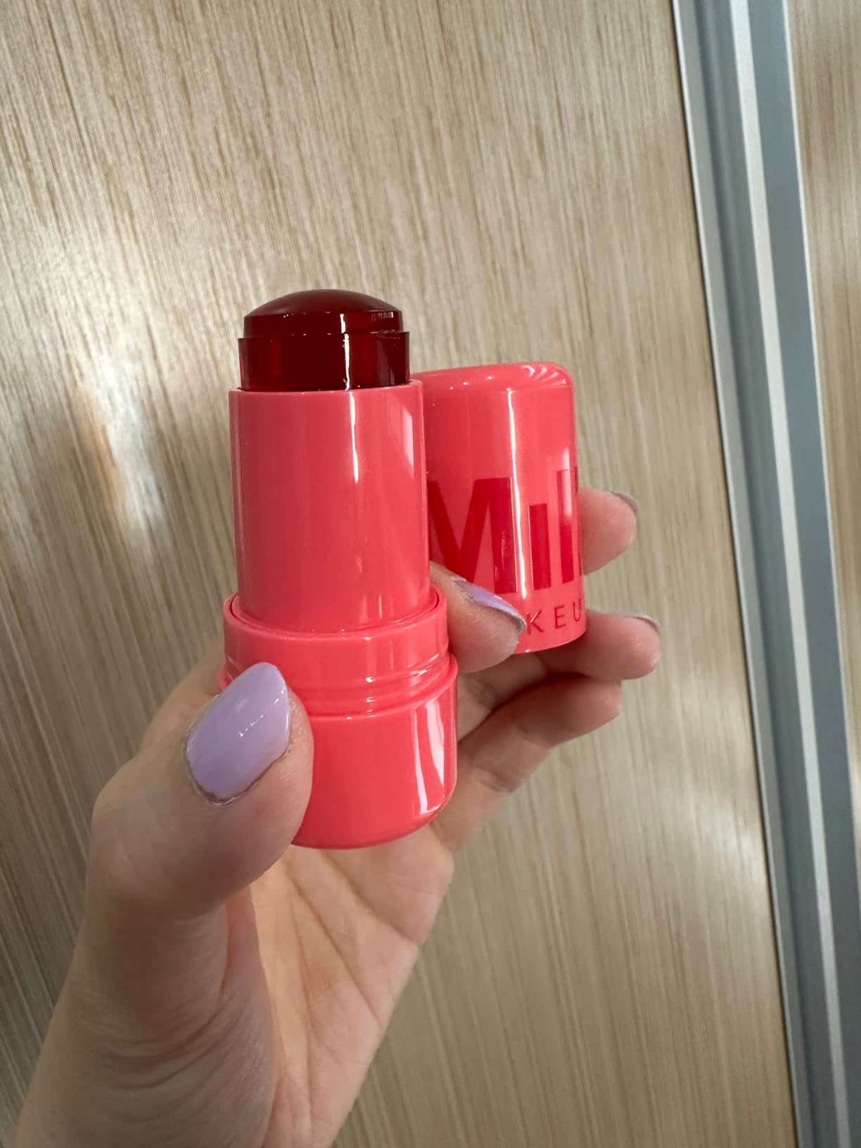 Hand holding a red-tinted articulator  and feature  balm with 