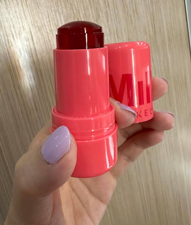 Hand holding a red-tinted articulator and feature balm with