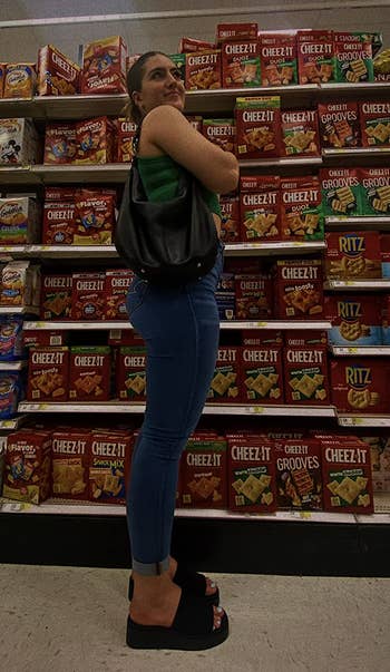 Person successful a market aisle holding a container stands adjacent shelves stocked with crackers and snacks