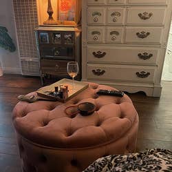 the same ottoman in rose pink, being used as a coffee table