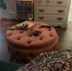 the same ottoman in rose pink, being used as a coffee table