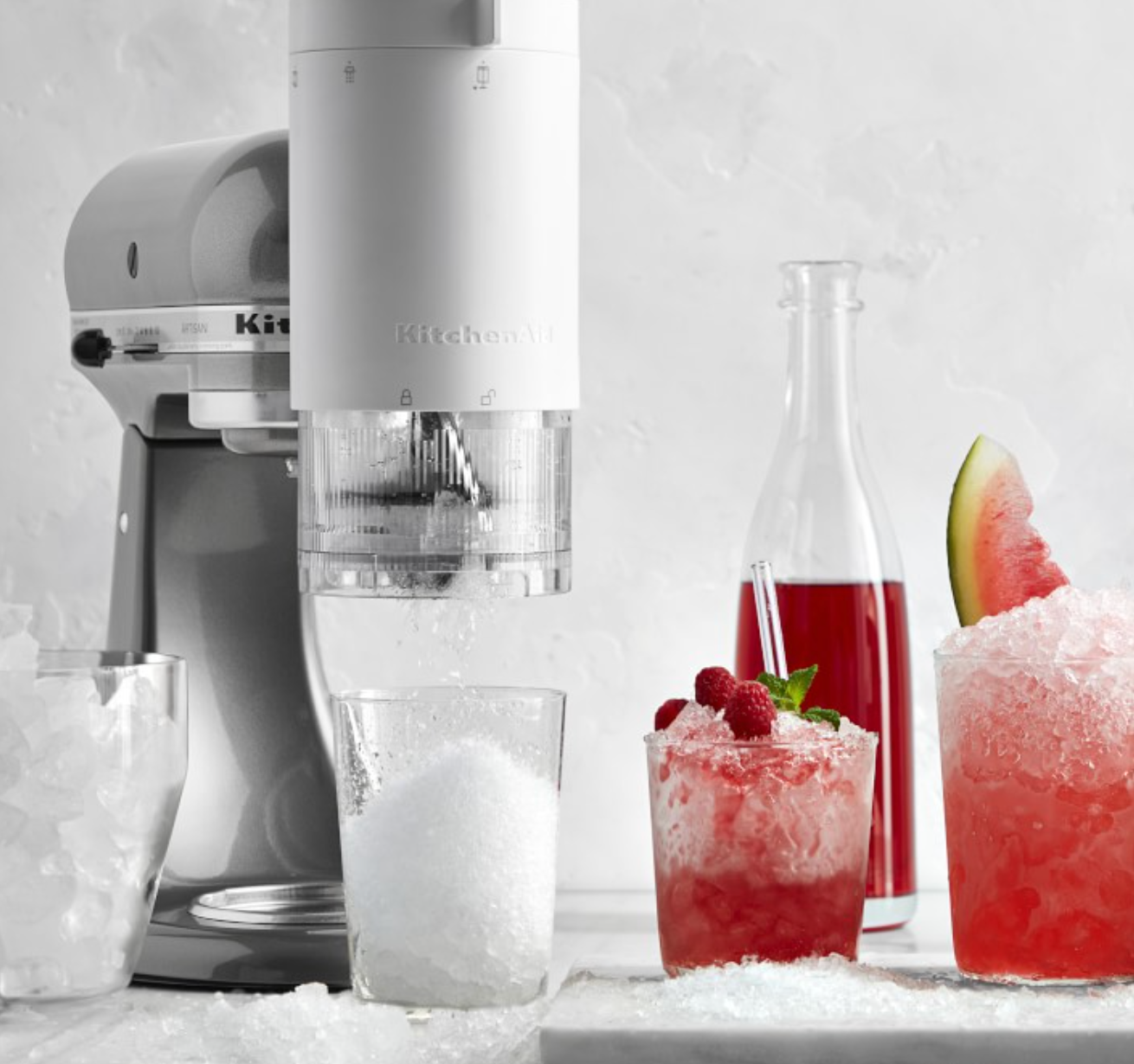 A white blender shaped attachment on KitchenAid that is dispensing ice 