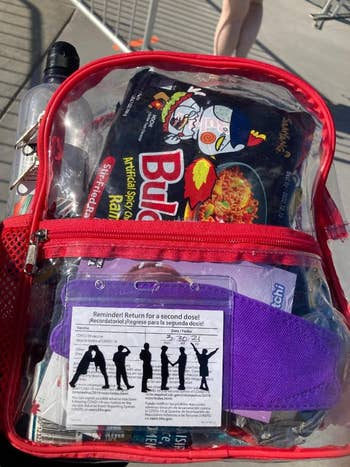 reviewer photo of red clear backpack with Buldak spicy noodle pack inside