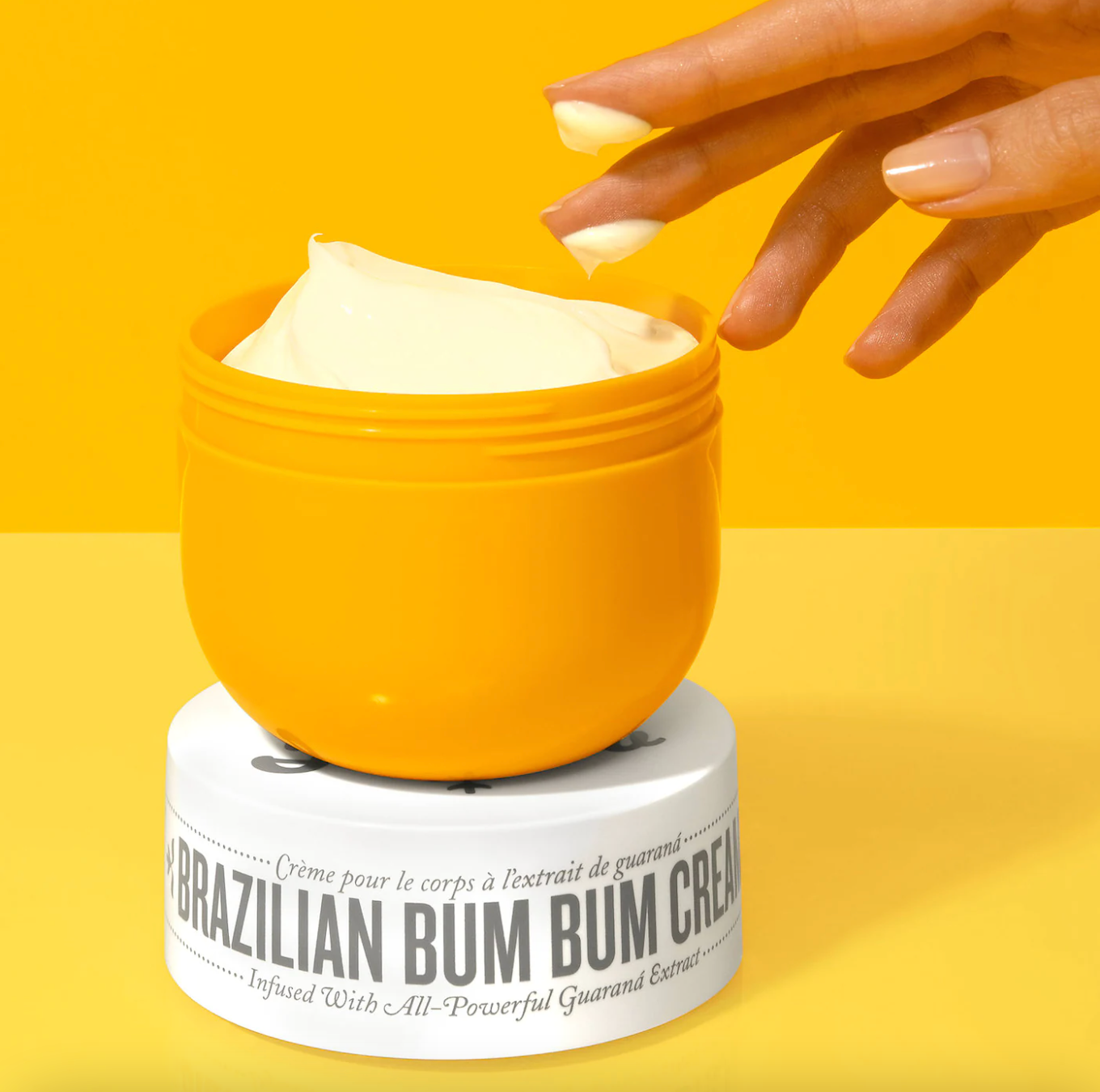 a model's hand reaching into a jar of brazilian bum bum