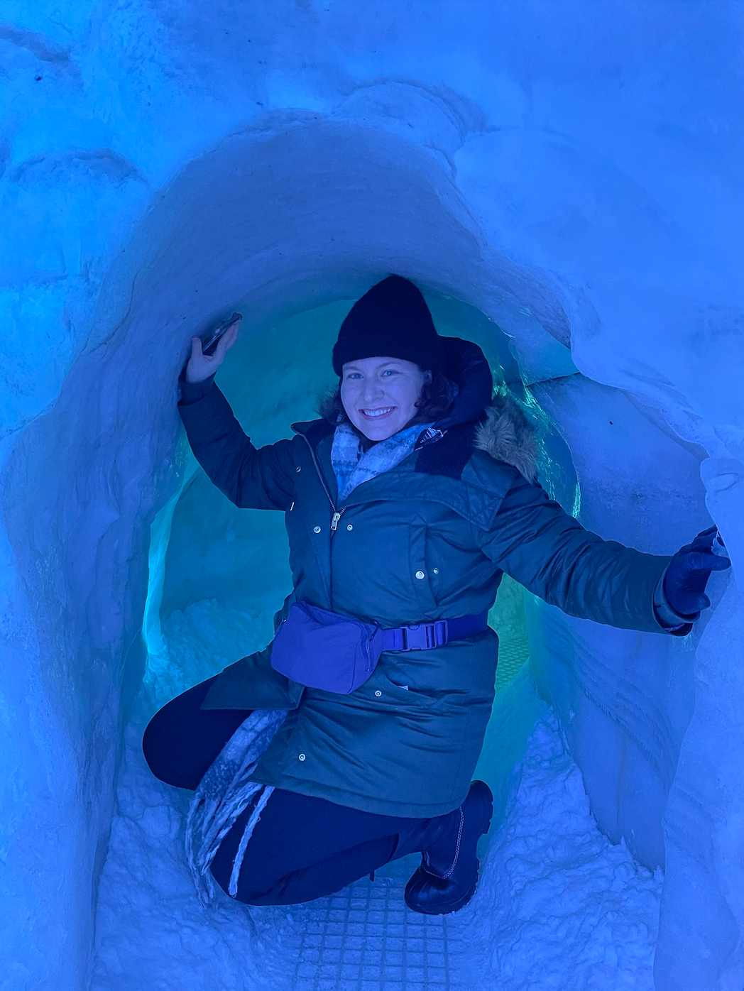 reviewer wearing the fanny pack over a heavy coat while posing in an ice cave