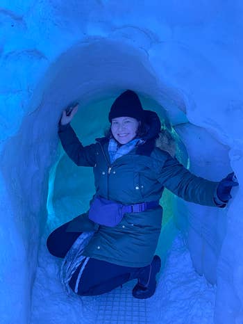 reviewer wearing the fanny pack over a heavy coat while posing in an ice cave