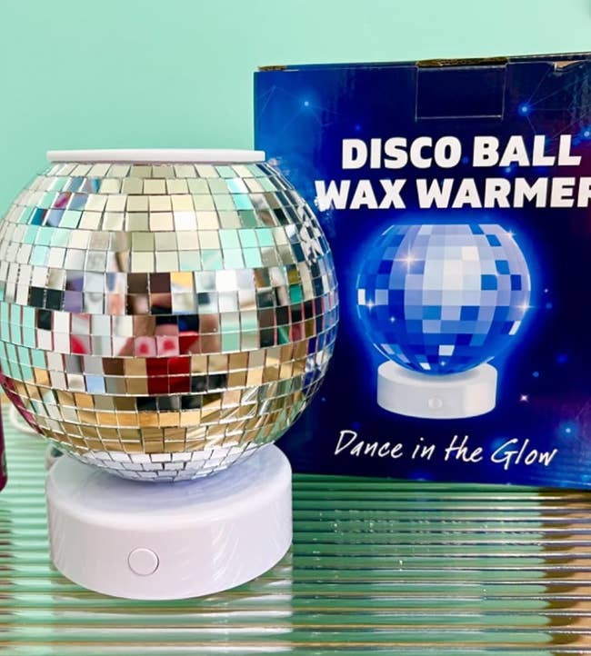 Disco ball wax warmer with a reflective exterior, next to its packaging displaying the product and the tagline 