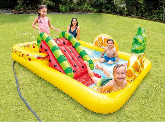 Children playing on an inflatable water slide in a backyard