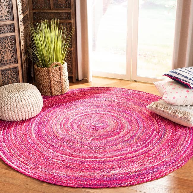 A braided round rug with threads of hot pink, pastel, and slight purple 