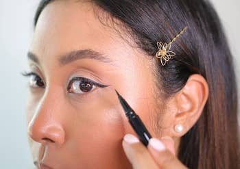 a reviewer applying a winged eyeliner with the nyx liquid eyeliner