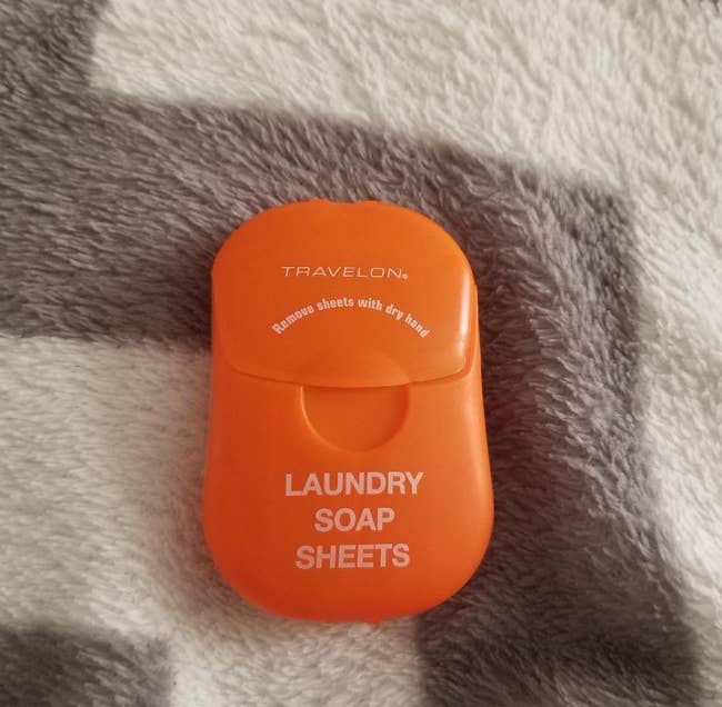 reviewer photo of the orange pack of laundry soap sheets on top of a blanket
