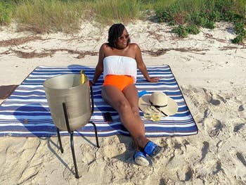 image of reviewer lounging on blue striped blanket at the beach