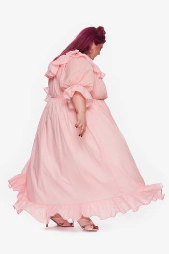 a side view of the pink dress with ruffled sleeves and hem 