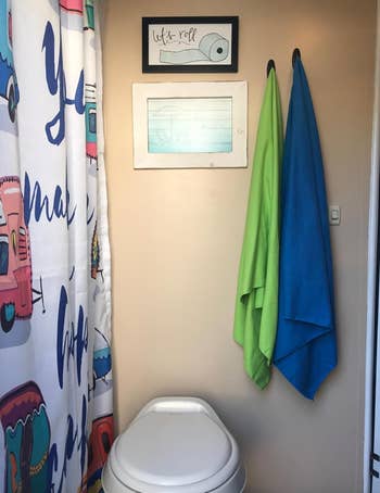 A bright green and bright blue towel hung up in a hotel bathroom 