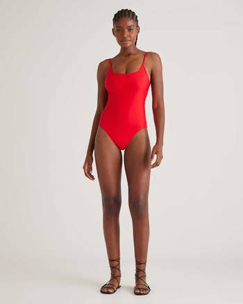 Model wearing a sleek swimsuit with bladed straps, paired with lace-up sandals, lasting confidently