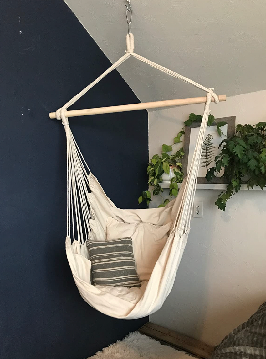 A beige single person hammock hanging from a wall 