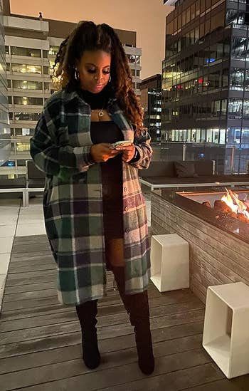 Reviewer successful a greenish plaid overgarment and achromatic boots stands by a rooftop occurrence pit, looking astatine her phone, surrounded by metropolis buildings astatine night