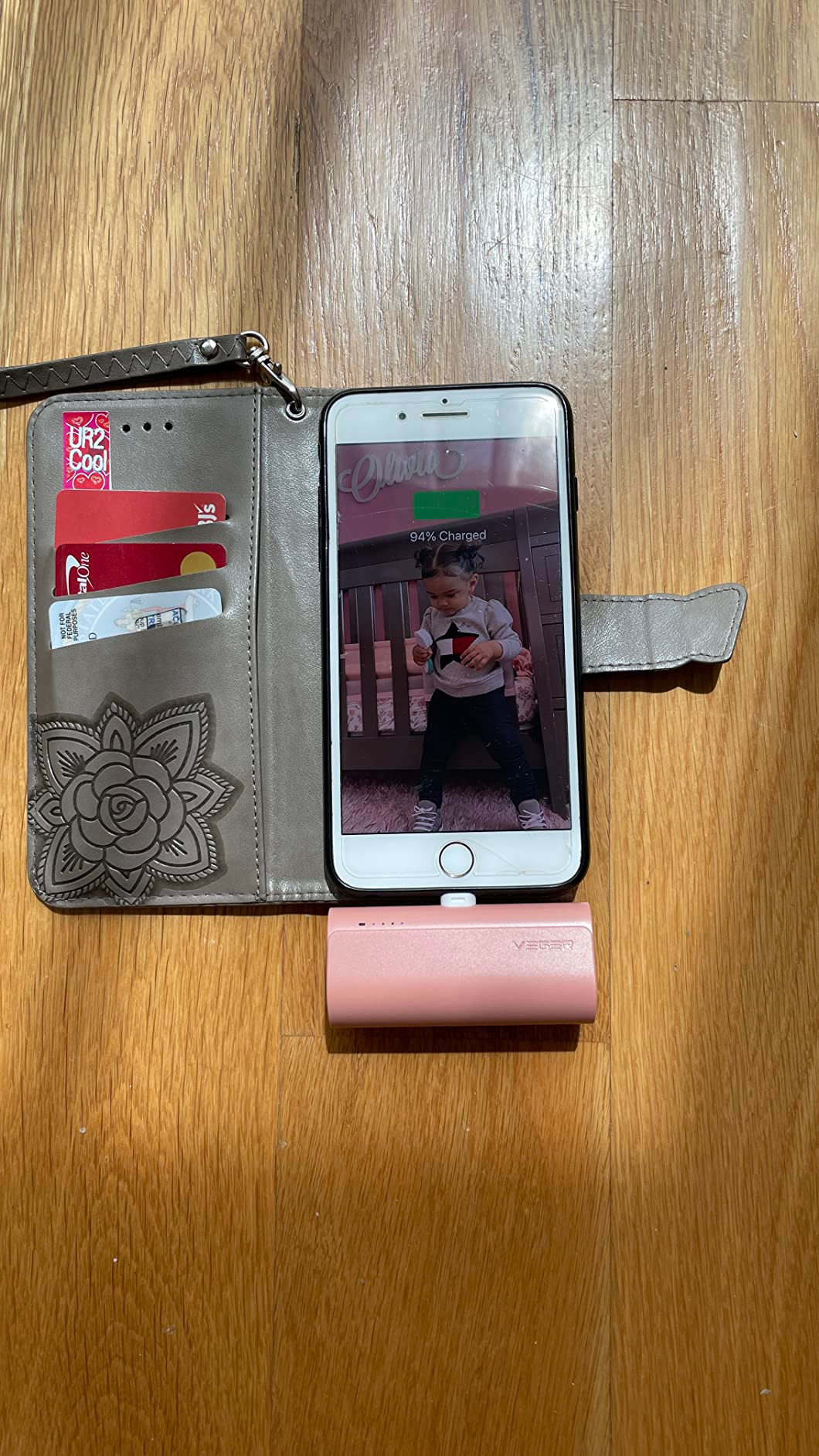 A smartphone placed in a wallet case with a portable charger charged into the phone