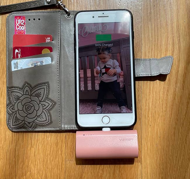 A smartphone placed in a wallet case with a portable charger charged into the phone
