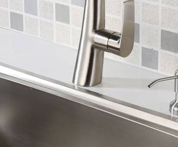 brushed nickel soap dispenser installed next to sink faucet