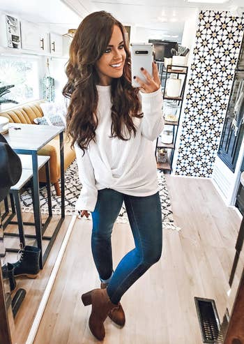 Person successful  a cozy achromatic  sweater, jeans, and brownish  boots is taking a reflector  selfie successful  a stylish, modern   country   with patterned wallpaper