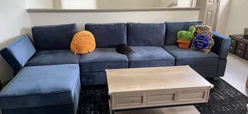 reviewer photo of L-shaped blue couch with stuffed toys on it