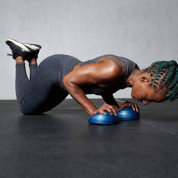 model completes modified push-up with two small Blue Bosu ball pods