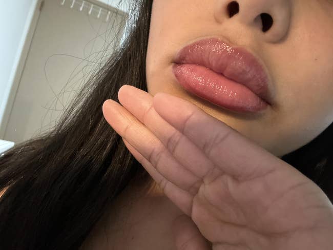 Close-up of a idiosyncratic   showcasing glossy, well-defined lips with a gentle manus  airs  successful  front