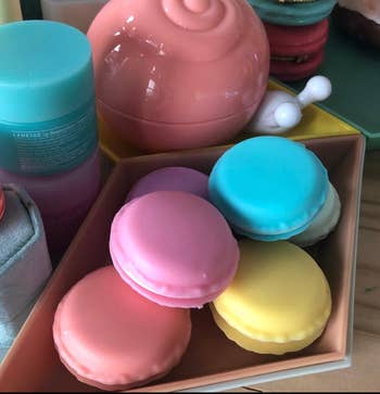 Assorted macaron-shaped cosmetic sponges in a box, next to skincare products