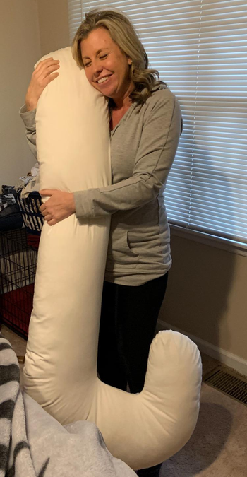Reviewer holding the white Snoogle pregnancy pillow