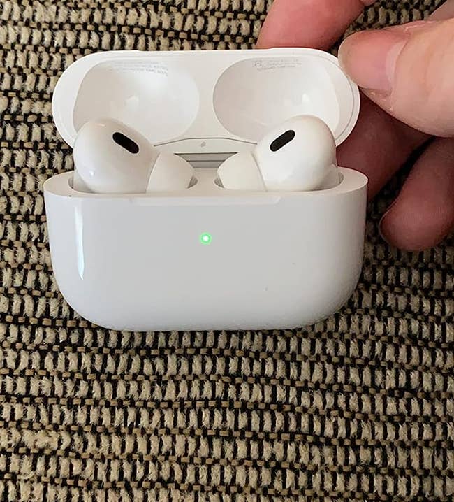 A reviewer holding the airpod case open with the airpods charging inside