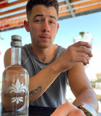 photo of nick jonas next to a bottle of villa one tequila