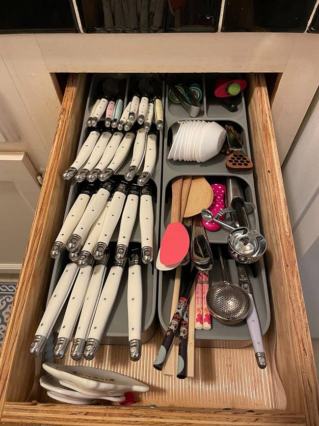 the gray silverware organizer with different-sized knives, forks, and spoons, along with chopsticks and ice cream scooper in neat kitchen drawer