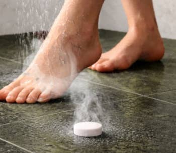 Foot successful ablution with steam rising from a dissolving tablet connected the floor, suggesting a spa oregon ablution product